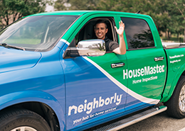 HouseMaster inspector waving inside branded truck.