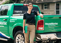 HouseMaster female inspector leaning on branded truck.