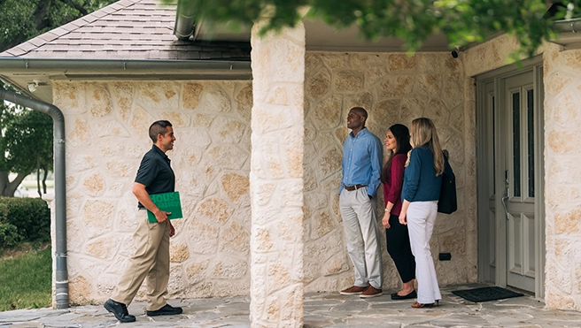 Technician with customers at front door of home.