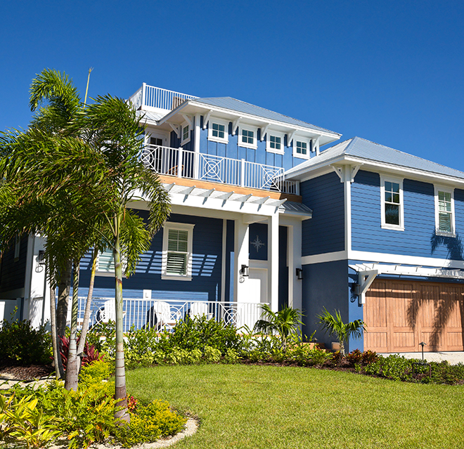 Blue two-story home with palm tree in front yard.