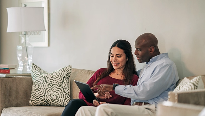 Man and woman on sofa, looking at laptop.