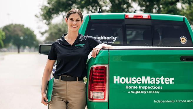 Female HouseMaster inspector leaning on branded truck.