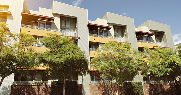 Modern condominium with trees in front.