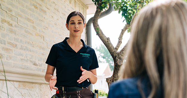 Technician speaking with customer outside of home.