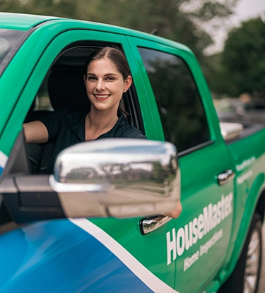 HouseMaster smiling female inspector inside branded truck.