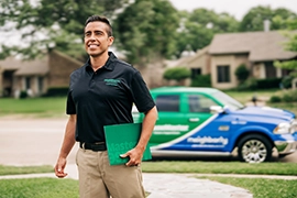 Smiling HouseMaster inspector walking with green folder in front of branded vehicle.