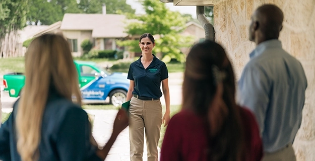 Smiling HouseMaster female inspector greeting 3 people.