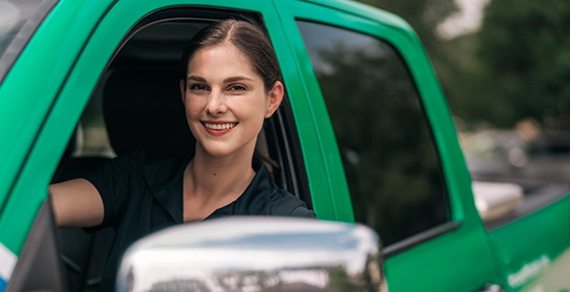 Smiling female HouseMaster inspector sitting inside branded work truck.