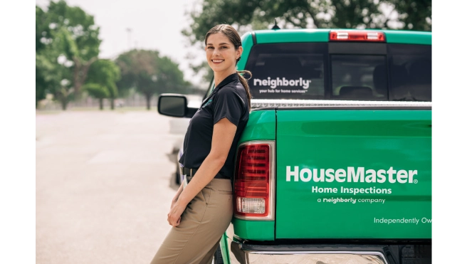 HouseMaster inspector leaning against branded vehicle.