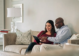 Two people sitting on couch looking at laptop.