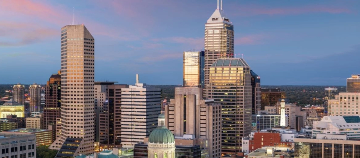Dusk view of Indianapolis city skyline with towering buildings illuminated by fading light.