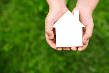 A person holding a small white house.