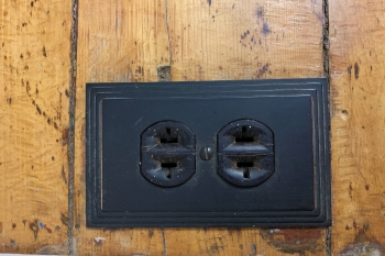 A black electrical outlet on a wood surface.