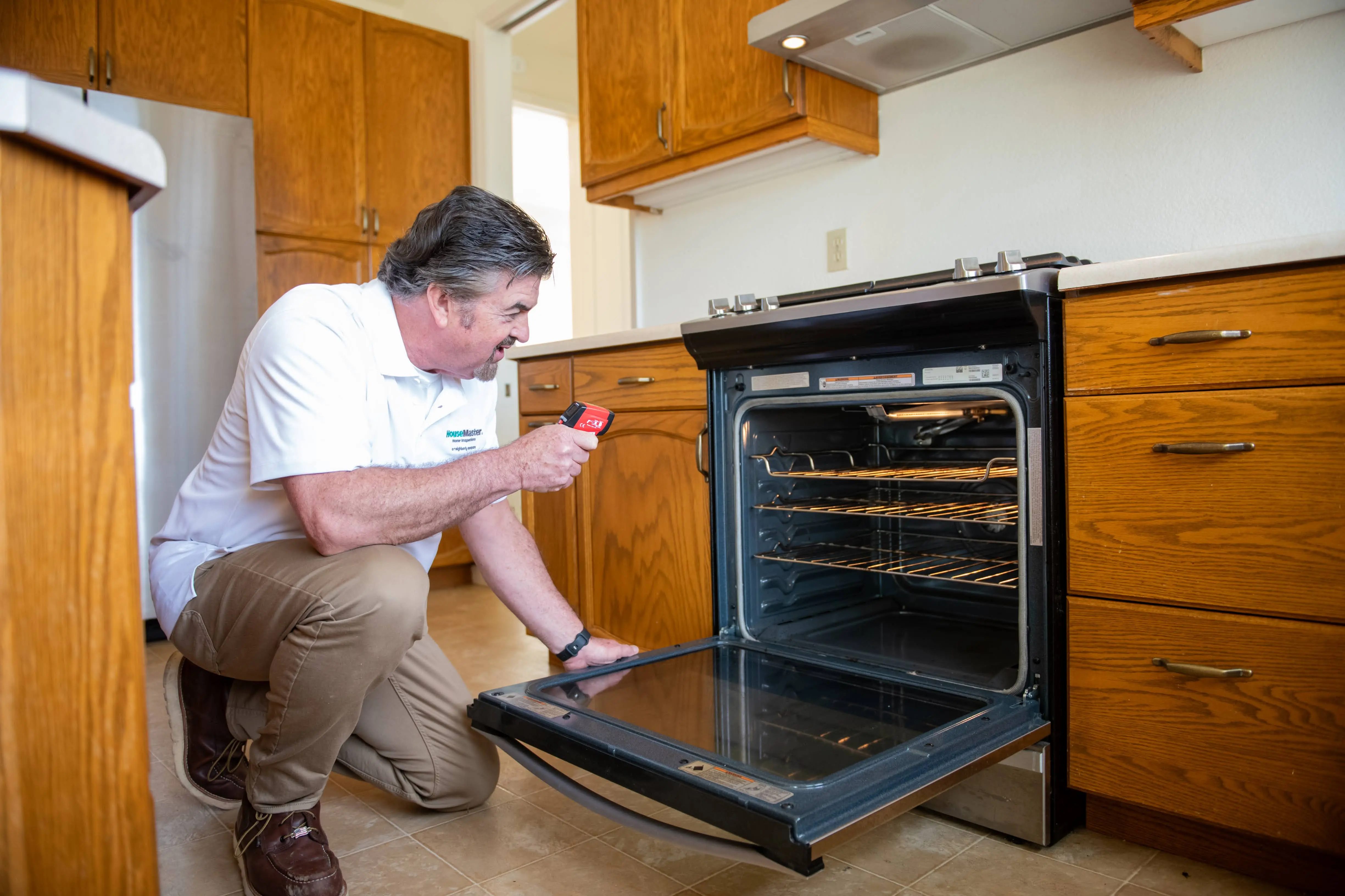 HouseMaster technician inspecting a kitchen appliance.