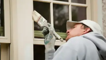 House painter brushing window trim.