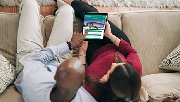Two homeowners sitting on a couch reviewing HouseMaster website.